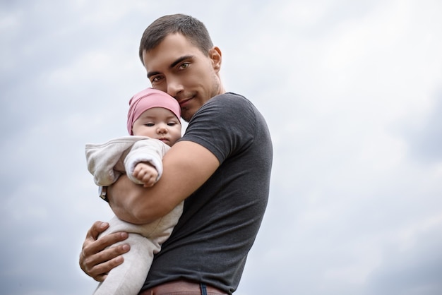 Père avec bébé sur son bras à l'air frais, marchant avec bébé