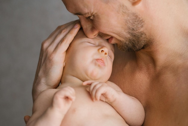 Un père caucasien heureux tient son bébé dans ses bras et l'embrasse avec soin