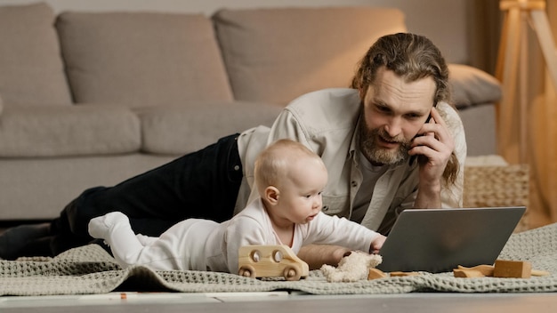 Père caucasien multitâche travaillant à domicile avec quarantaine pour ordinateur portable avec petit bébé