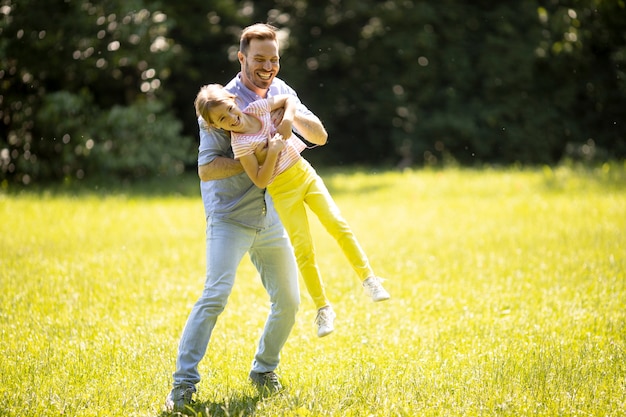 Père chassant sa petite fille mignonne tout en jouant dans le parc