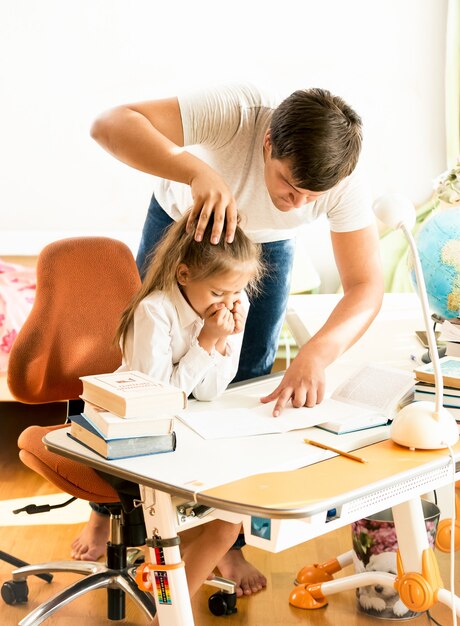 Père en colère pointant du doigt l'erreur sur le cahier des filles