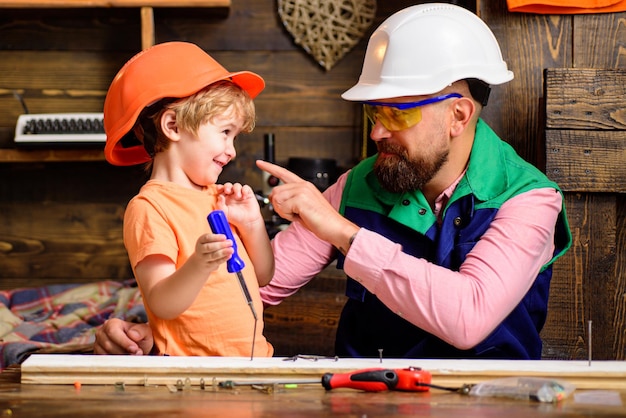 Père de construction d'outils apprenant à son petit fils à utiliser des outils de menuisier et martelant le père aidant ainsi