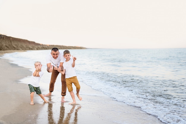 Père et deux fils montrent la classe, côte de la mer. Profiter des vacances