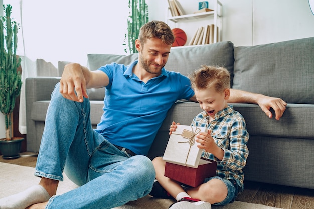 Père donne un cadeau en boîte à son petit fils à la maison