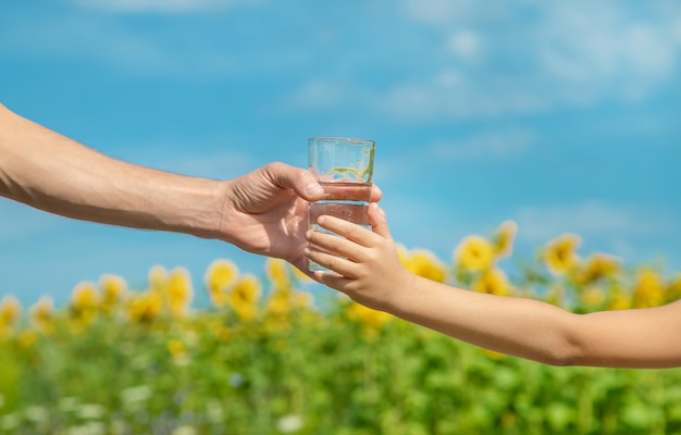 Le père donne de l'eau à l'enfant à l'arrière-plan du champ