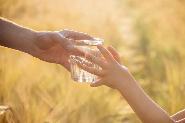 Le père donne à l&#39;enfant un verre d&#39;eau. Mise au point sélective.