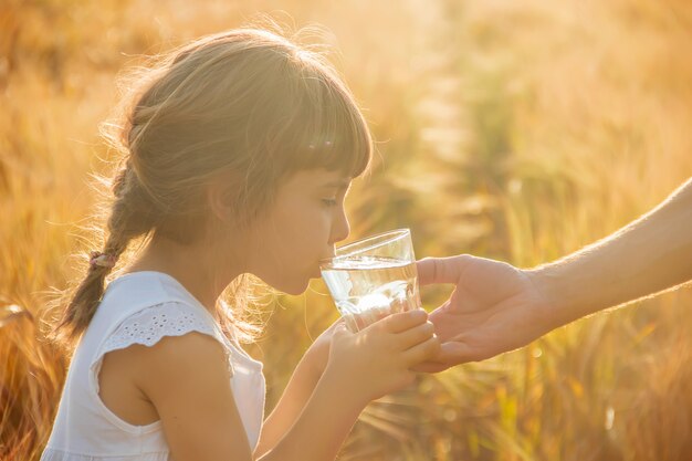 Le père donne à l&#39;enfant un verre d&#39;eau. Mise au point sélective.