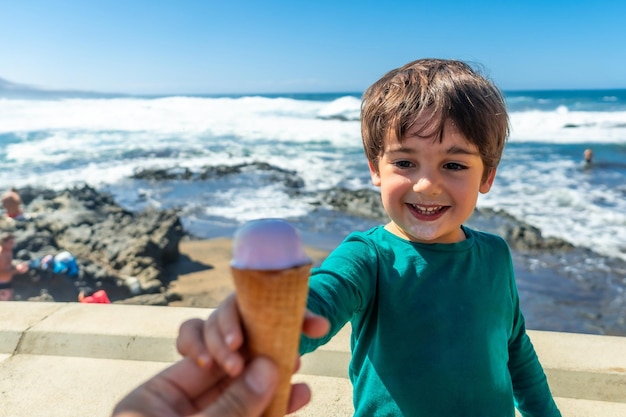 Un père donne à son enfant une délicieuse crème glacée au bord de la mer en été.