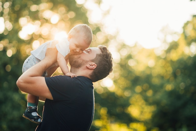 Père embrassant son bébé dans le parc