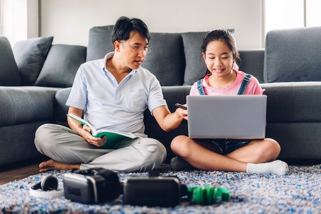 Père et enfant asiatique petite fille apprendre et regarder un ordinateur portable faire ses devoirs étudier les connaissances avec l'éducation en ligne e-learning system. Vidéoconférence pour enfants avec professeur tuteur à la maison