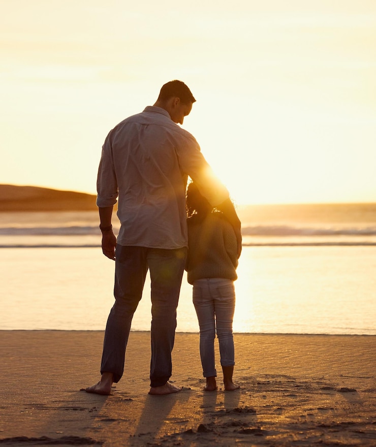 Photo père enfant et câlin à la plage pour les soins au coucher du soleil et des vacances pendant l'été avec vue sur le soleil et l'eau père enfant et relation à l'extérieur pour l'amour enfance et vacances avec voyage lien et embrasser