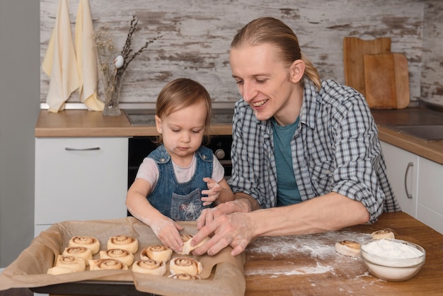 Père et enfant, cuire des cannelle sur la cuisine avec plaisir