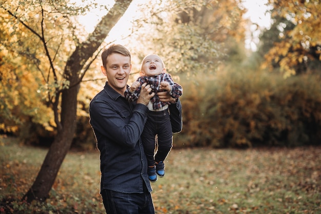 Père avec un enfant dans un magnifique parc d'automne