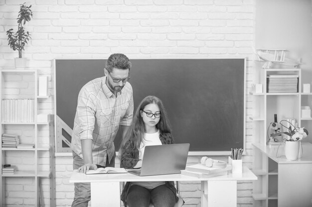 Père et enfant nerd étudient à l'école avec un ordinateur portable sur une étude de fond de tableau noir