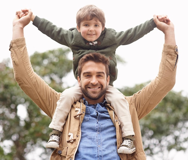Père enfant et portrait sur les épaules dans la nature pour le bonheur la liaison de liaison ou de vacances Personne masculin fils et visage au parc de l'environnement pour l'amour en plein air en tant que soins parentaux détendus ou ensemble