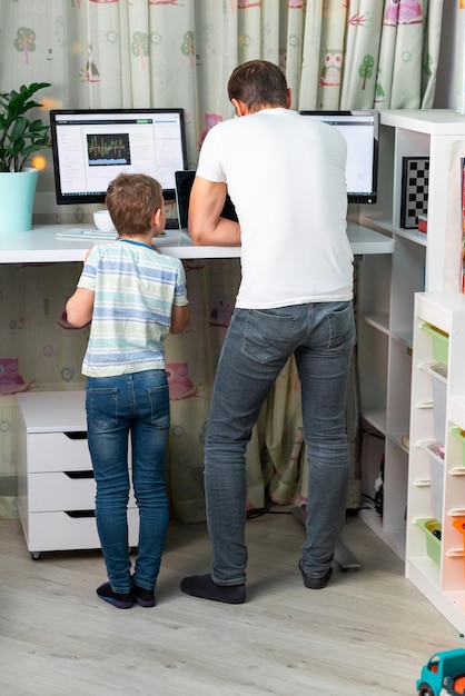 Père avec enfant travaillant à domicile au bureau debout pendant la quarantaine Indépendant avec enfants travaillant à domicile Table de bureau haute et confortable pour un dos sain