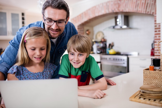 Père Et Enfants à L'aide D'un Ordinateur Portable Dans La Cuisine