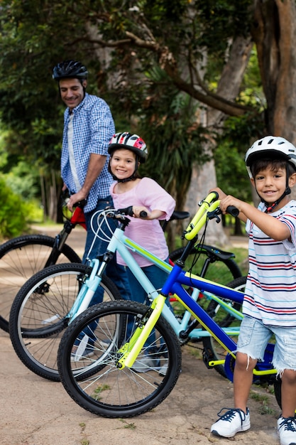 Père et enfants debout avec vélo dans le parc