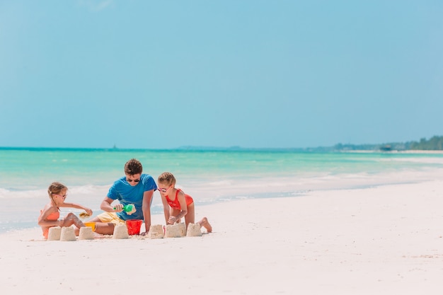 Père et enfants faisant château de sable sur la plage tropicale. Famille, jouer, plage, jouets