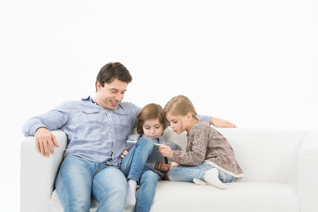 Père avec enfants jouant au pavé tactile à la maison. Enseignement à domicile.