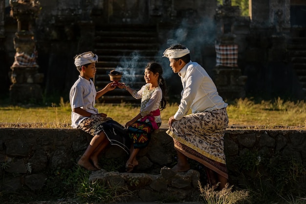 Un père avec des enfants organise une cérémonie rituelle. Bali. Indonésie