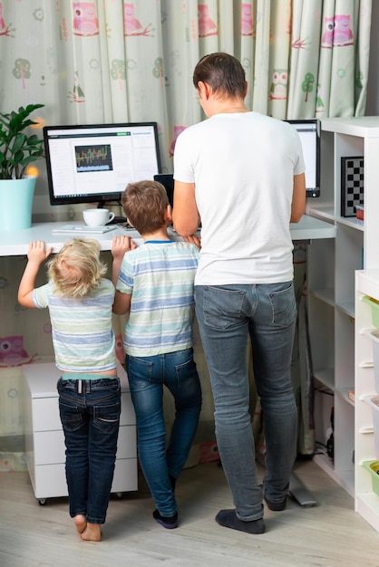 Père avec des enfants travaillant à domicile au bureau debout pendant la quarantaine Indépendant avec des enfants travaillant à domicile Table de bureau haute et confortable pour un dos sain