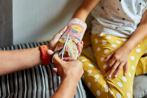 Un père enlève un plâtre d'une adolescente avec un bras cassé.