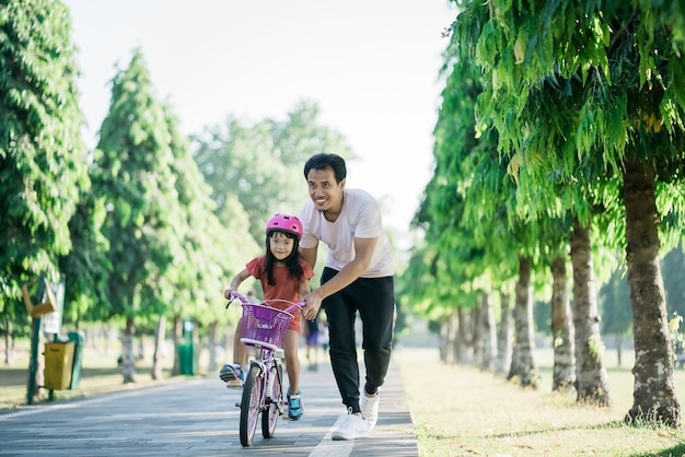 Père enseignant à sa fille à faire du vélo dans le parc