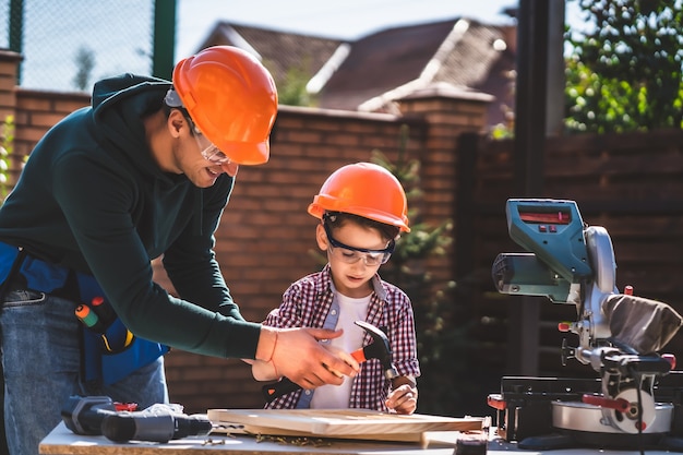 Le père enseigne à son fils comment utiliser un marteau et des clous