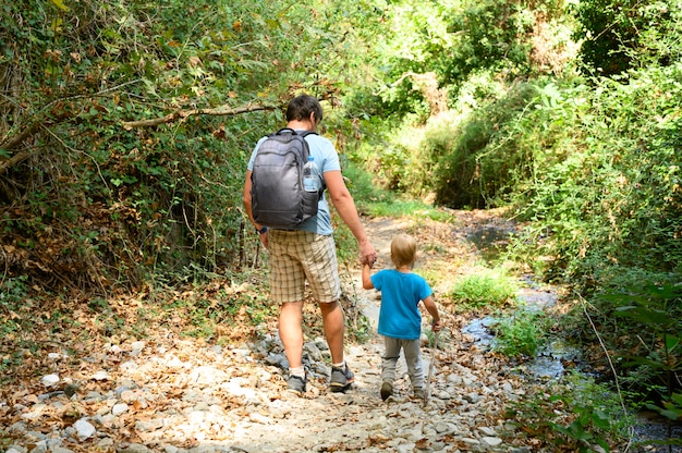 père ensemble son fils enfant et sa famille lors d'une randonnée à travers une gorge de montagne surmonte les obstacles. vacances dans la nouvelle normale.