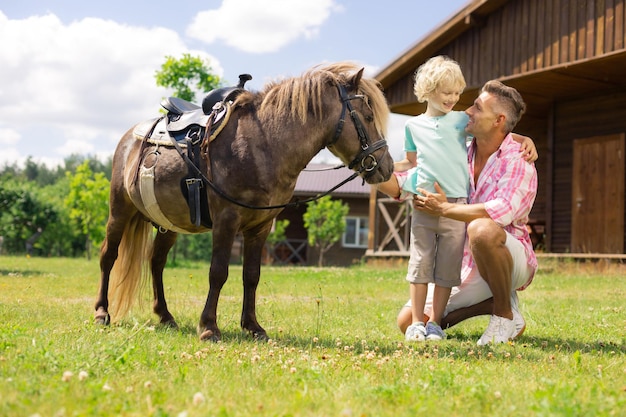 Père étreignant son fils tout en se rapprochant du cheval ensemble