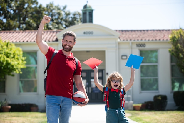 Père excité marchant son fils à l'école Parent étonné et élève d'écolier de l'école primaire avec sac à dos