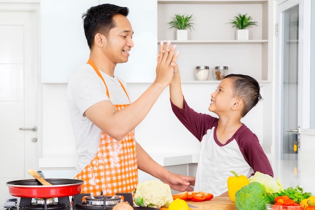 Père faisant un high five avec son fils dans la cuisine