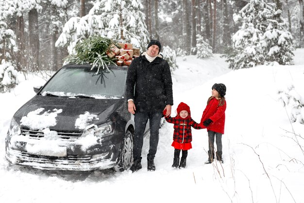 Le père fait une grimace en montrant sa langue aux enfants à côté de l'arbre de Noël