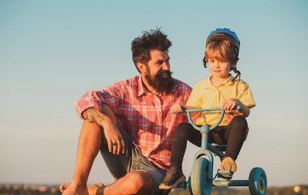 Un père de famille aimant et son fils papa aident son enfant à faire du vélo