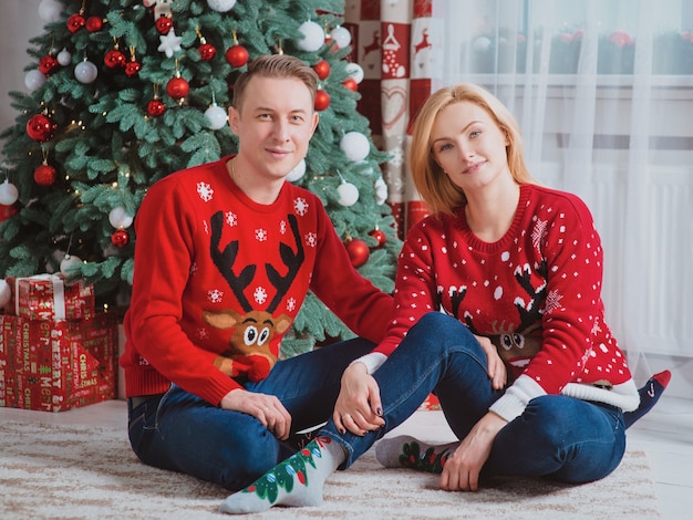 père de famille caucasien mère et petite fille en pulls de noël près de l'arbre de noël