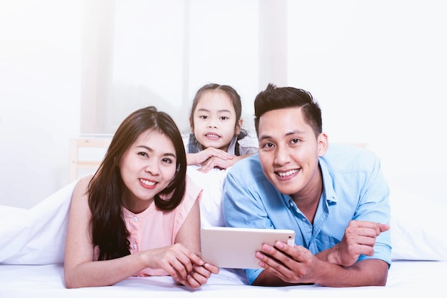 Père de famille heureux, mère et petite fille sur le lit à la maison, famille heureuse d&#39;amour asiatique.