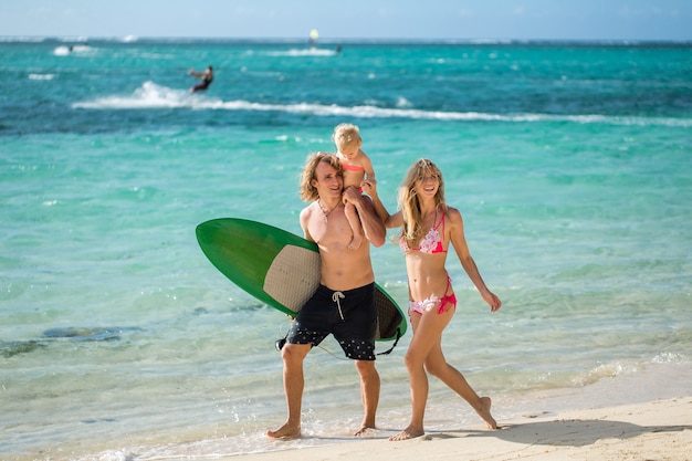 Père de famille sportive, maman et fille marchant sur la plage