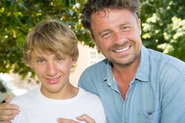 Photo père fier et souriant avec son fils adolescent à l'extérieur