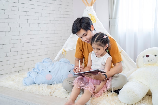 Père et fille apprenant et jouant avec un ordinateur portable à la maison