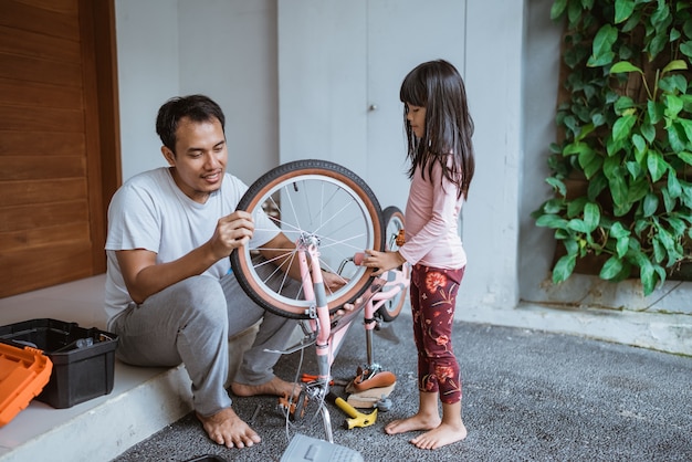 Père et fille asiatiques réparant le vélo ensemble