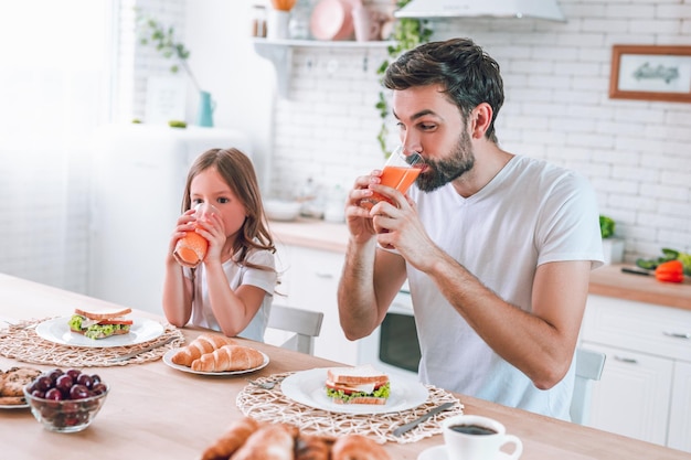 Père et fille buvant du jus pour le petit déjeuner le matin