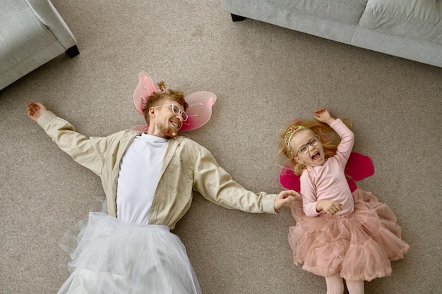 Père et fille habillés drôles allongés sur le sol