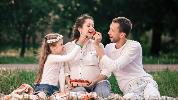 Un père et une fille heureux nourrissent des fraises de maman lors d'un pique-nique
