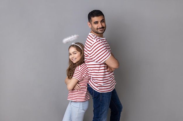 Père et fille homme et enfant avec halo au-dessus de la tête debout dos à dos avec les mains jointes