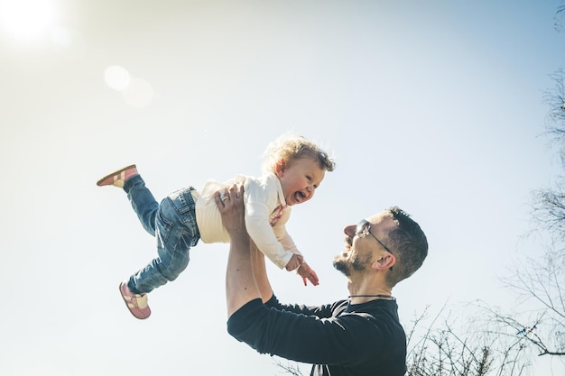 Un père et une fille joyeux contre le ciel