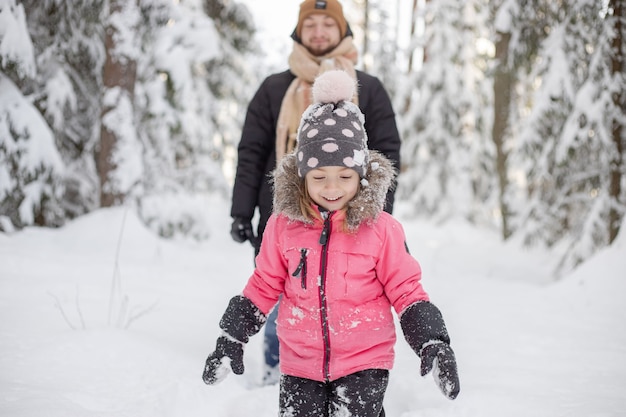 Père et fille marchant et s'amusant dans la forêt enneigée en hiver