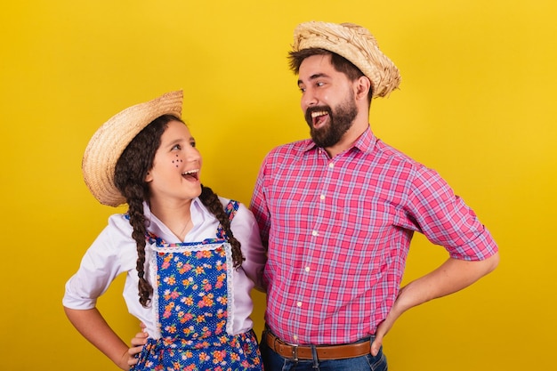 Père et fille portant des vêtements typiques pour Festa Junina avec la main sur la taille Pour la fête d'Arraia