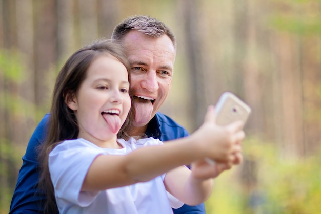 Père et fille prenant selfie sur smartphone à l'extérieur