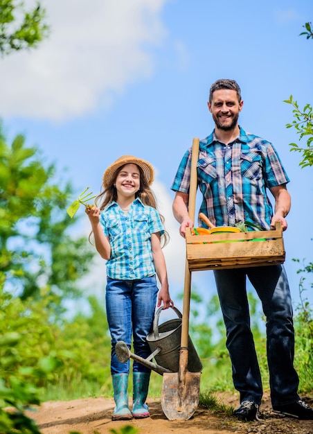 Père et fille sur rancho agriculture d'été agriculteur homme avec petite fille outils de jardin pelle et arrosoir enfant travailleur avec papa famille liaison printemps campagne village arrosage des fleurs